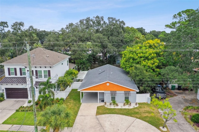 view of front of home featuring driveway, roof with shingles, a front yard, and fence