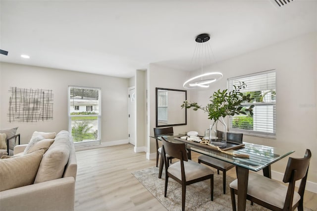 dining room with a wealth of natural light, a chandelier, light wood-style flooring, and baseboards