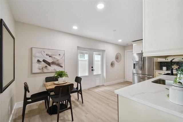 kitchen with tasteful backsplash, stainless steel fridge with ice dispenser, light wood-type flooring, recessed lighting, and white cabinetry