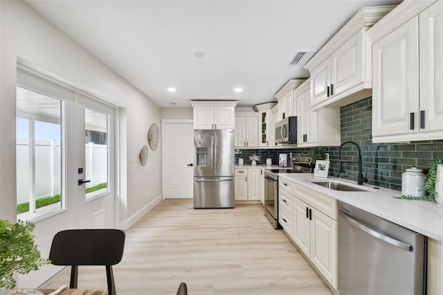 kitchen featuring visible vents, light countertops, decorative backsplash, stainless steel appliances, and a sink