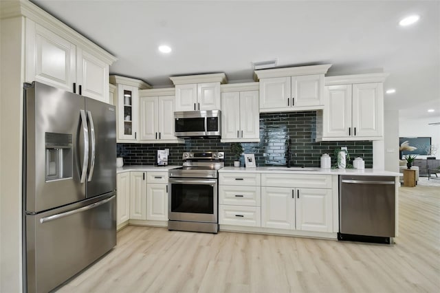 kitchen with a sink, light countertops, light wood-style flooring, and stainless steel appliances