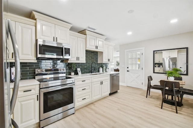 kitchen featuring light countertops, light wood-style flooring, appliances with stainless steel finishes, and a sink