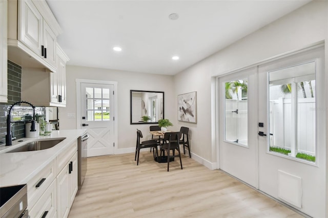 kitchen featuring recessed lighting, a sink, white cabinets, light wood-style floors, and stainless steel dishwasher