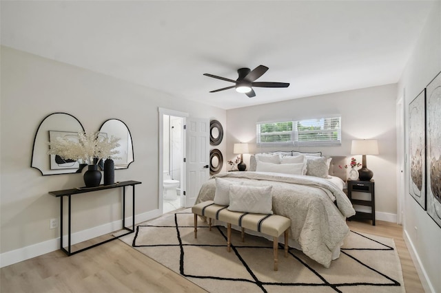 bedroom with ensuite bath, ceiling fan, baseboards, and light wood-style floors