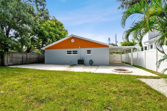 back of house with a lawn, a fenced backyard, an outdoor fire pit, and a patio area