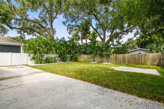 view of yard featuring a patio, a fenced backyard, and driveway