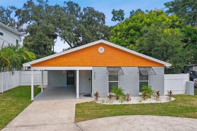 view of front of home featuring a carport, fence, brick siding, and a front yard