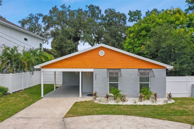 view of front of home with a carport, fence, concrete driveway, a front yard, and brick siding