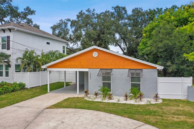 view of front facade featuring brick siding, a front lawn, fence, a carport, and driveway