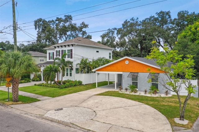 view of front of property featuring a front lawn, concrete driveway, fence, and brick siding