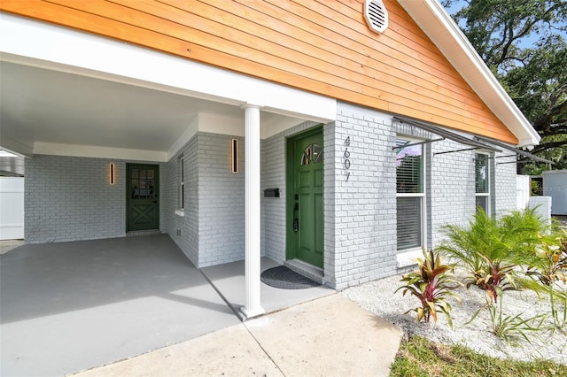 doorway to property with a carport and brick siding