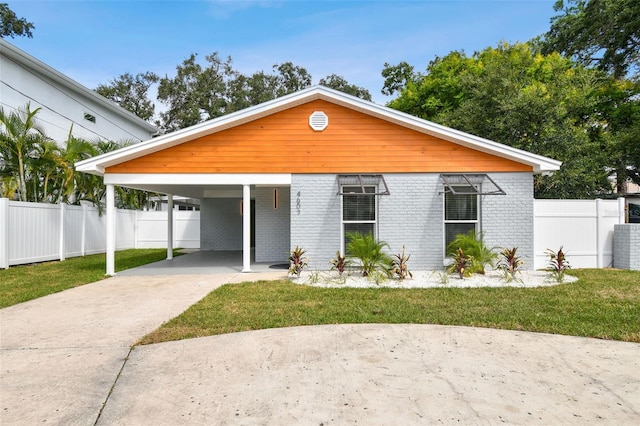 view of front of home featuring concrete driveway, fence, brick siding, and a front lawn