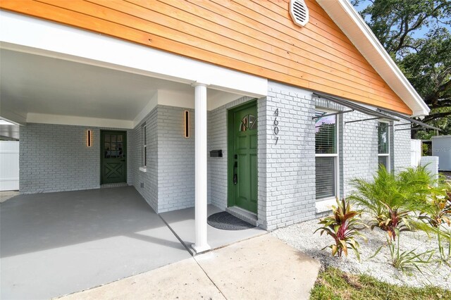 doorway to property featuring a carport and brick siding