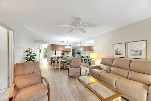 living room featuring light wood-type flooring, a textured ceiling, and ceiling fan