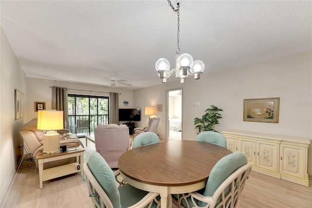 dining room featuring ceiling fan with notable chandelier, a textured ceiling, and light wood-type flooring