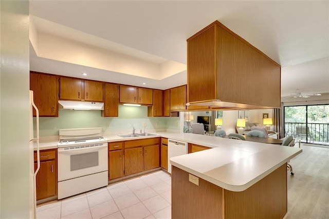 kitchen featuring white appliances, kitchen peninsula, ceiling fan, and sink