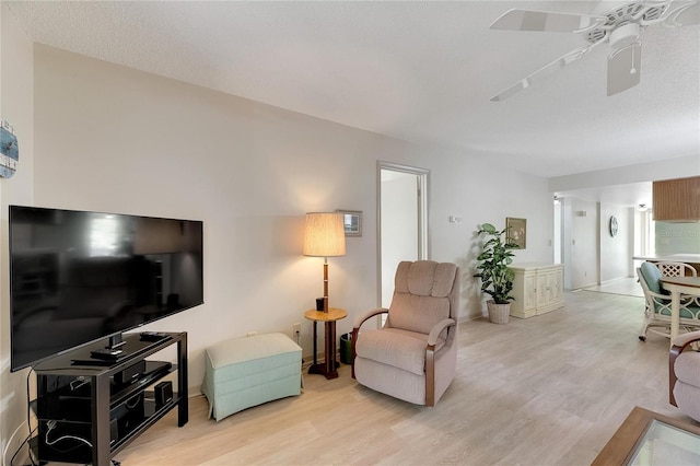 living room with a textured ceiling, light hardwood / wood-style floors, and ceiling fan