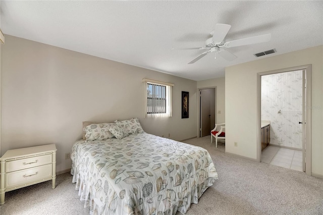 carpeted bedroom featuring ceiling fan, a textured ceiling, and ensuite bath