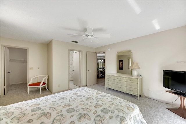 carpeted bedroom with ceiling fan, a closet, ensuite bath, and a walk in closet