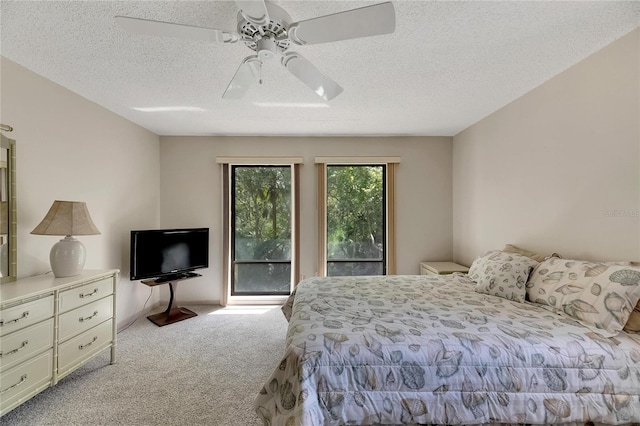 carpeted bedroom featuring ceiling fan and a textured ceiling