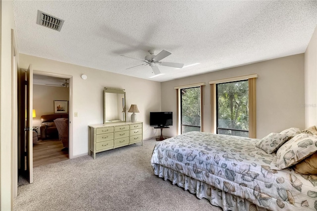 carpeted bedroom with ceiling fan and a textured ceiling