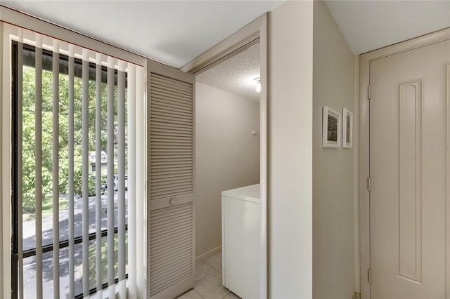 laundry room with a textured ceiling, light tile patterned floors, and washer / dryer