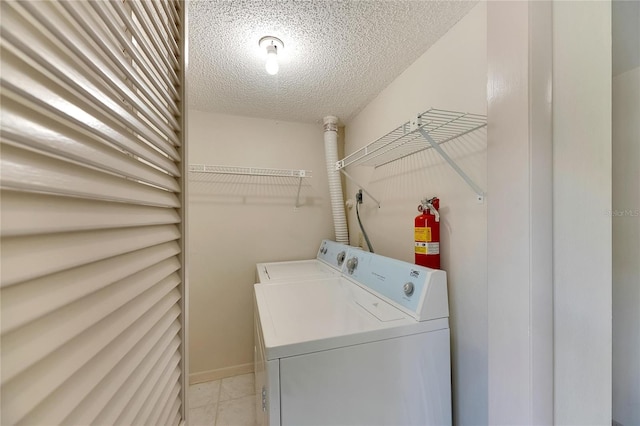 laundry area with separate washer and dryer, a textured ceiling, and light tile patterned floors