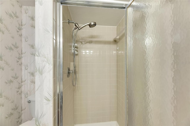 bathroom featuring a shower with door and toilet