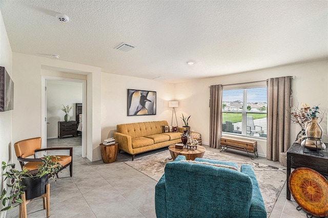 living room with a textured ceiling and light tile patterned floors