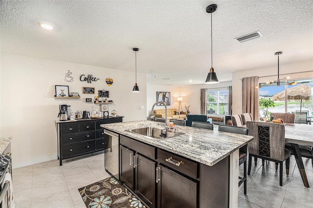 kitchen featuring a textured ceiling, sink, an island with sink, and decorative light fixtures