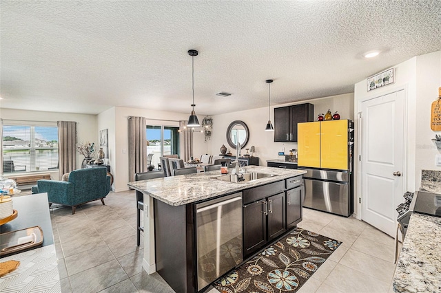 kitchen featuring light stone countertops, a kitchen island with sink, appliances with stainless steel finishes, and a healthy amount of sunlight