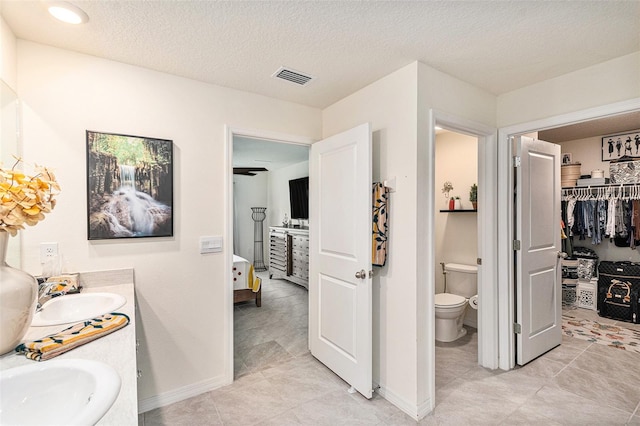 bathroom with a textured ceiling, tile patterned flooring, vanity, and toilet