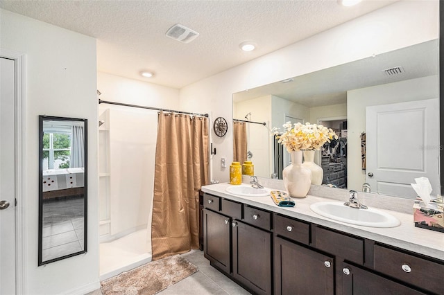 bathroom with walk in shower, vanity, a textured ceiling, and tile patterned floors