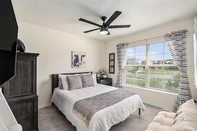 tiled bedroom with ceiling fan and a textured ceiling