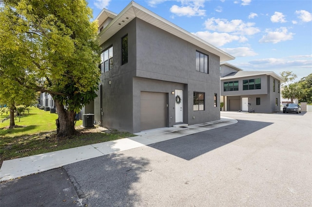 contemporary house featuring a front yard, central air condition unit, and a garage