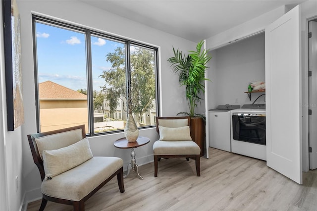 sitting room featuring light wood-type flooring, separate washer and dryer, and plenty of natural light