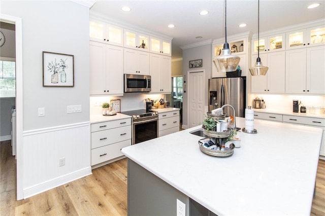 kitchen featuring appliances with stainless steel finishes, white cabinets, decorative light fixtures, and plenty of natural light