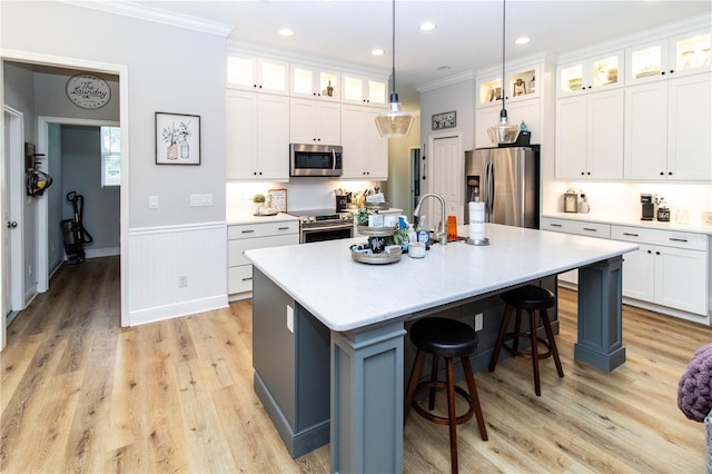 kitchen with a kitchen island with sink, stainless steel appliances, and white cabinets