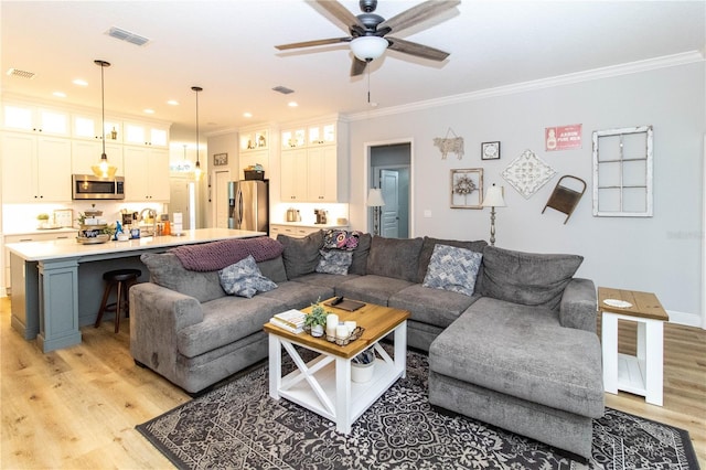 living room featuring light hardwood / wood-style flooring, ceiling fan, and crown molding