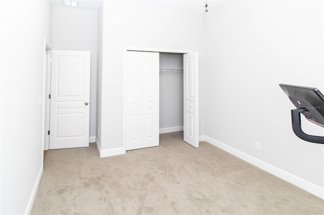 unfurnished bedroom featuring light carpet, a high ceiling, and a closet