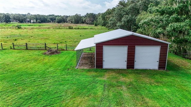 view of outdoor structure featuring a garage, a yard, and a rural view