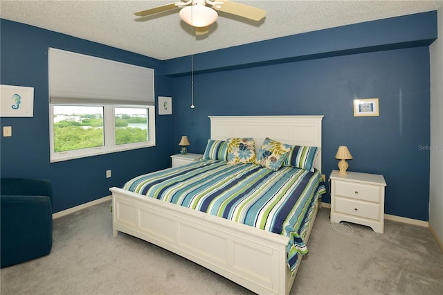 carpeted bedroom featuring ceiling fan and a textured ceiling