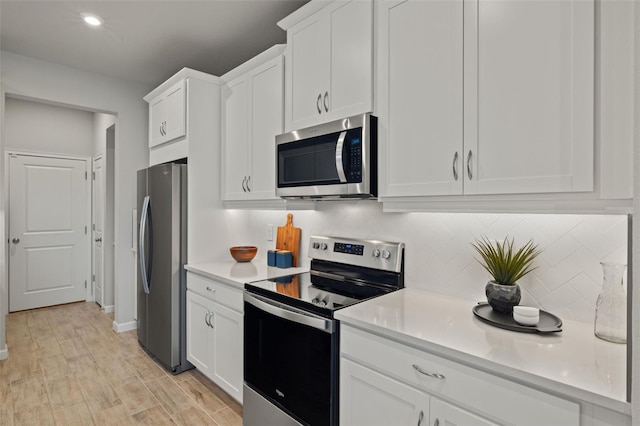 kitchen featuring decorative backsplash, white cabinetry, stainless steel appliances, and light wood-type flooring