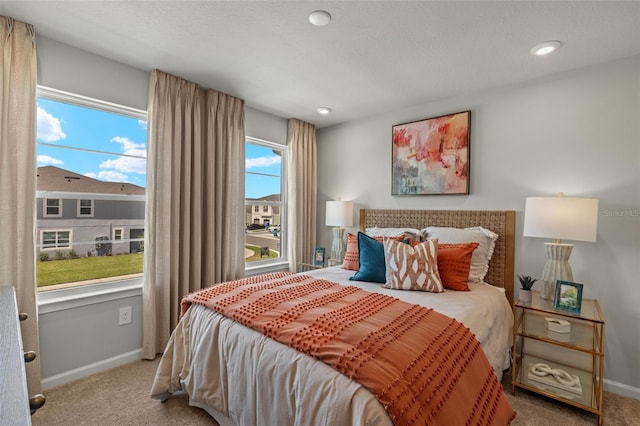 carpeted bedroom featuring a textured ceiling and multiple windows