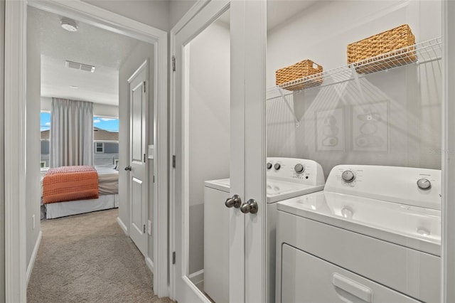 laundry room featuring a textured ceiling, washing machine and dryer, and light carpet