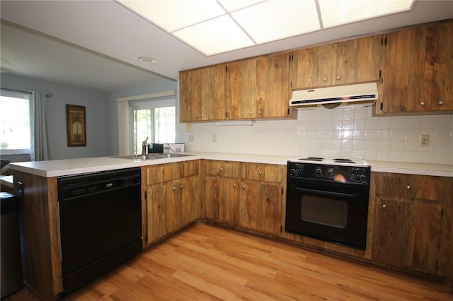 kitchen featuring black appliances, sink, light hardwood / wood-style flooring, tasteful backsplash, and kitchen peninsula