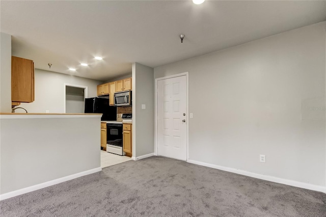 kitchen with decorative backsplash, black fridge, white range with electric cooktop, and light carpet