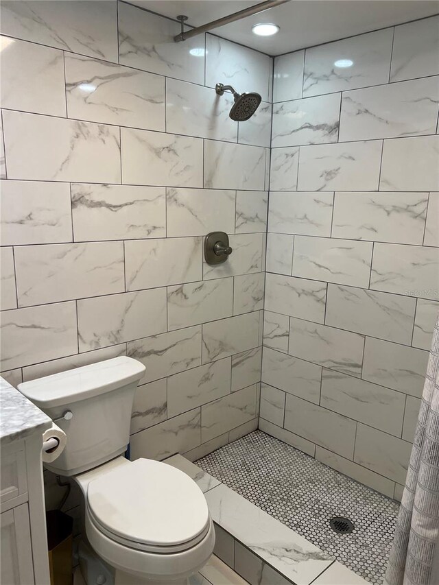 bathroom with tile walls, toilet, vanity, and curtained shower