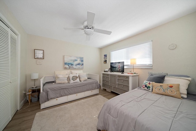 bedroom with light wood-type flooring, ceiling fan, and a closet