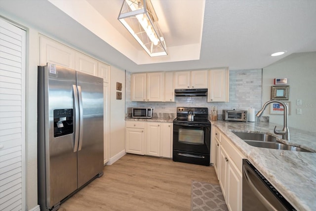 kitchen featuring light stone counters, sink, tasteful backsplash, light hardwood / wood-style flooring, and appliances with stainless steel finishes